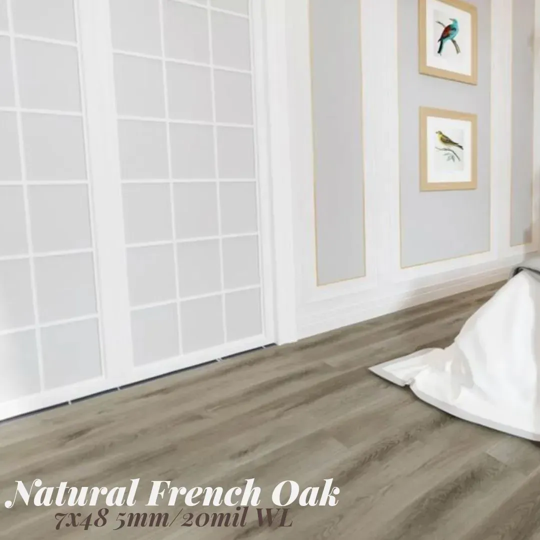 Bright white room with gray wood flooring, framed wall art, and a draped white cloth on the floor