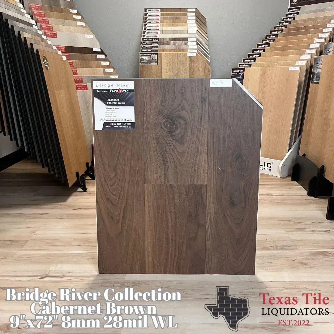 A dark brown wood-look flooring sample board displayed in a showroom by Texas Tile Liquidators.