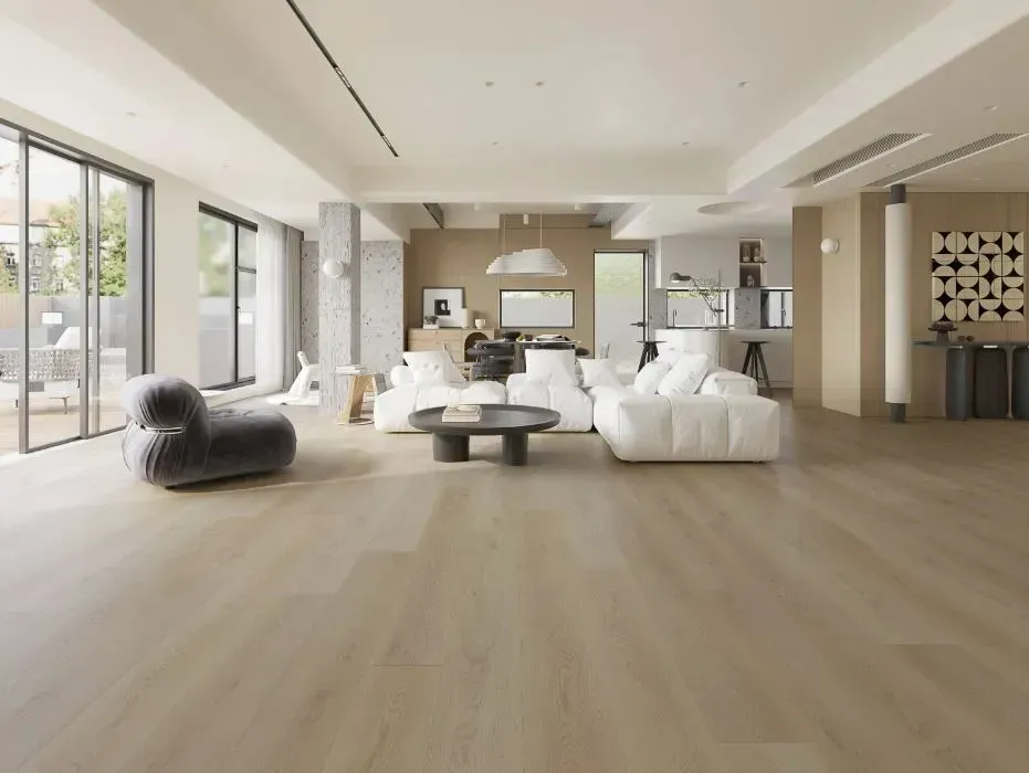 A bright, modern open-concept living area with light wood flooring, a white sectional sofa, and a gray armchair.