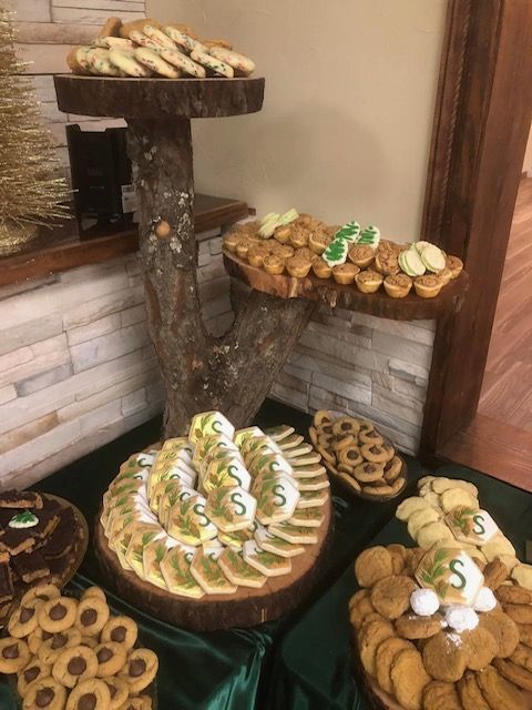 Cookie display: various cookies on wooden platters, green and gold accents, festive setting.