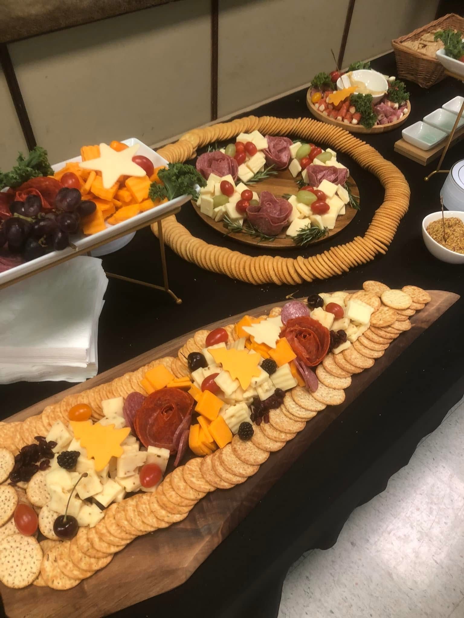 Charcuterie boards with cheese, meats, crackers, grapes, and tomatoes arranged on a table.