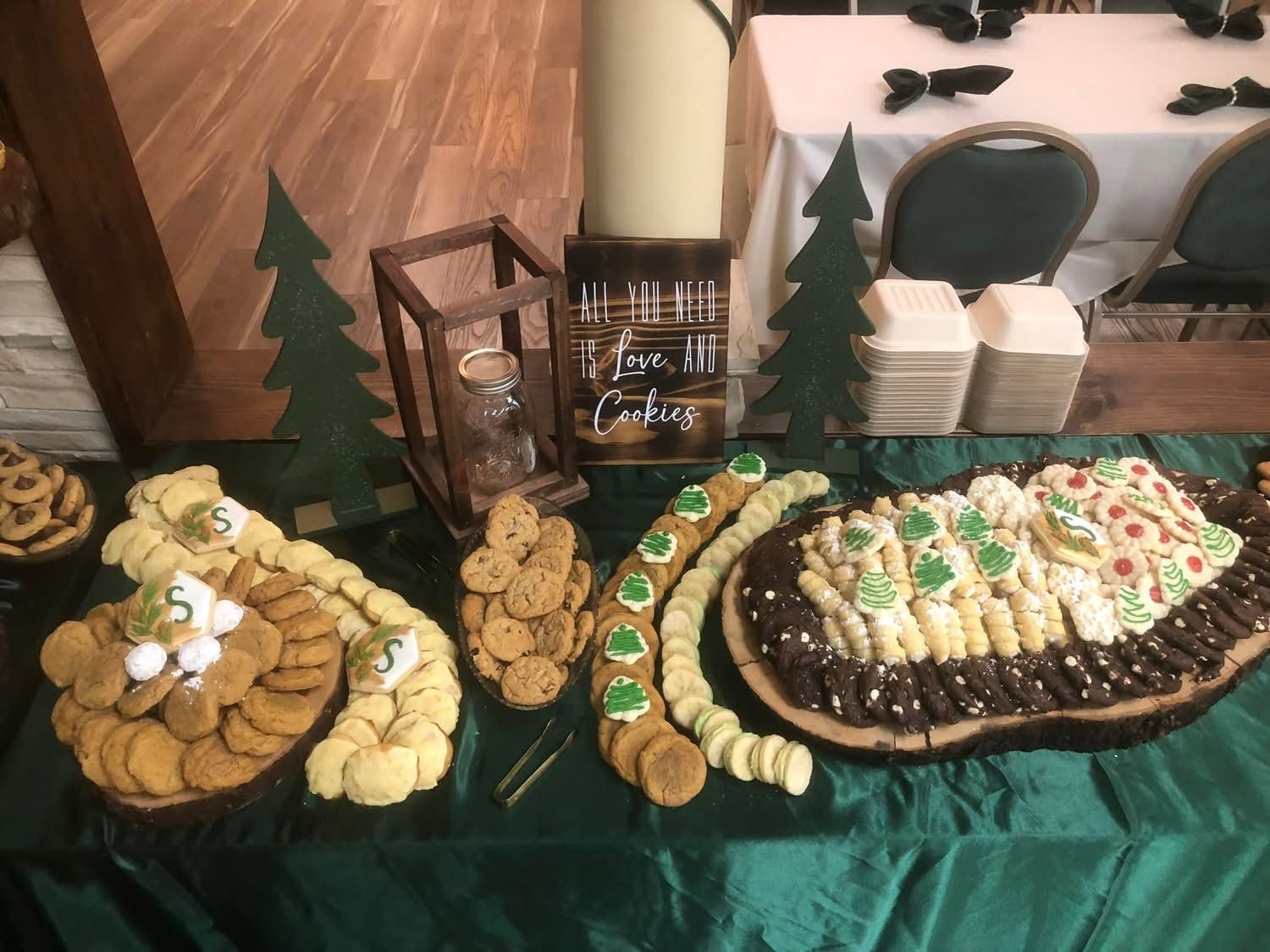 Cookie buffet: wood displays on a green tablecloth, decorated with wooden trees.