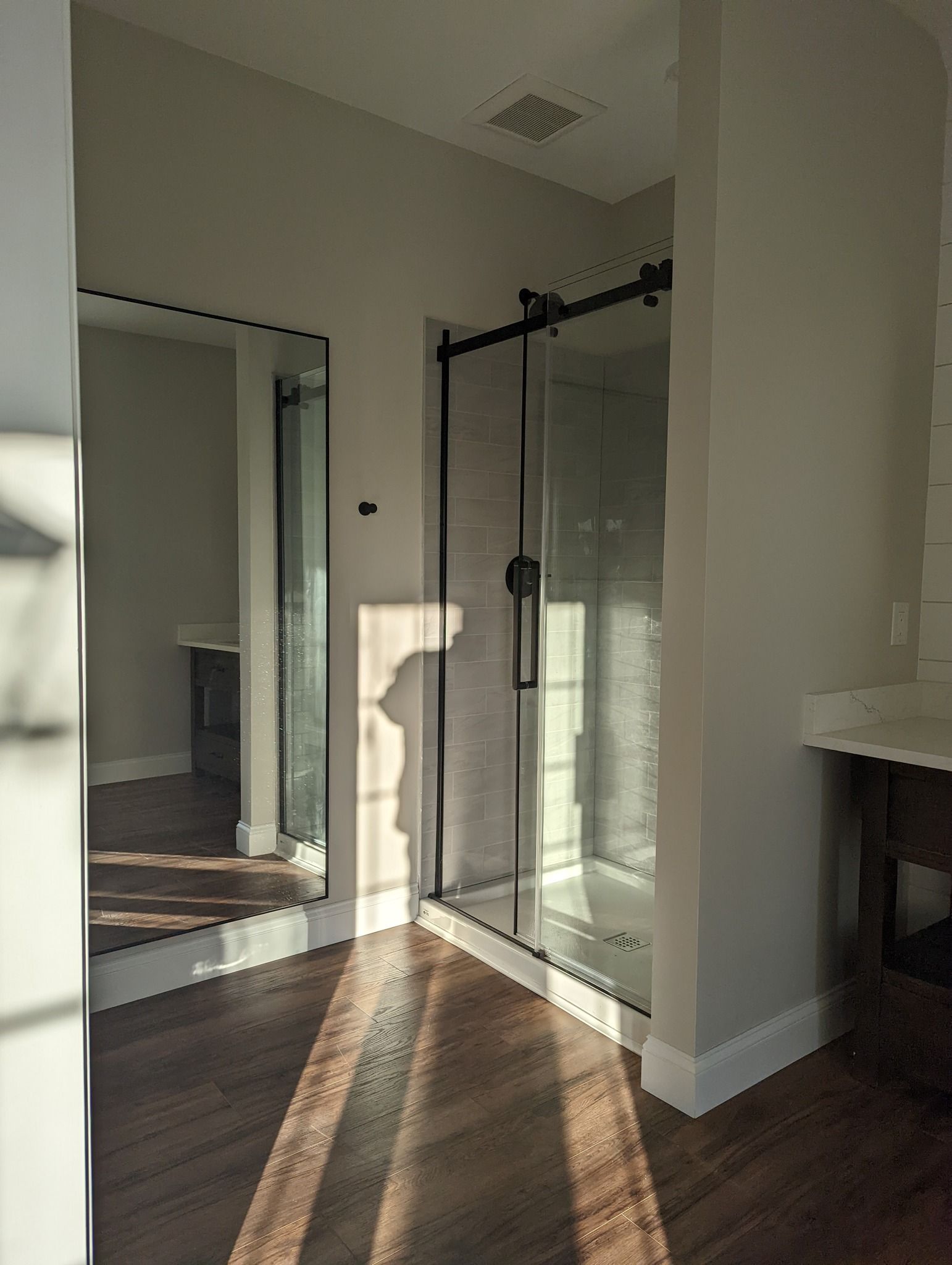 A bathroom with a sliding glass shower door and a large mirror.