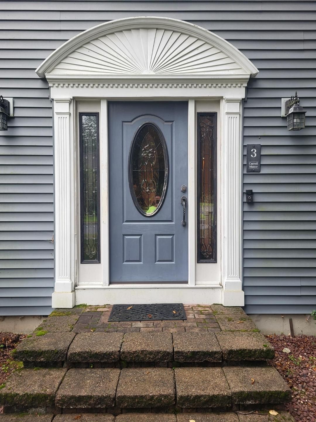 The front door of a house with a blue door and steps.