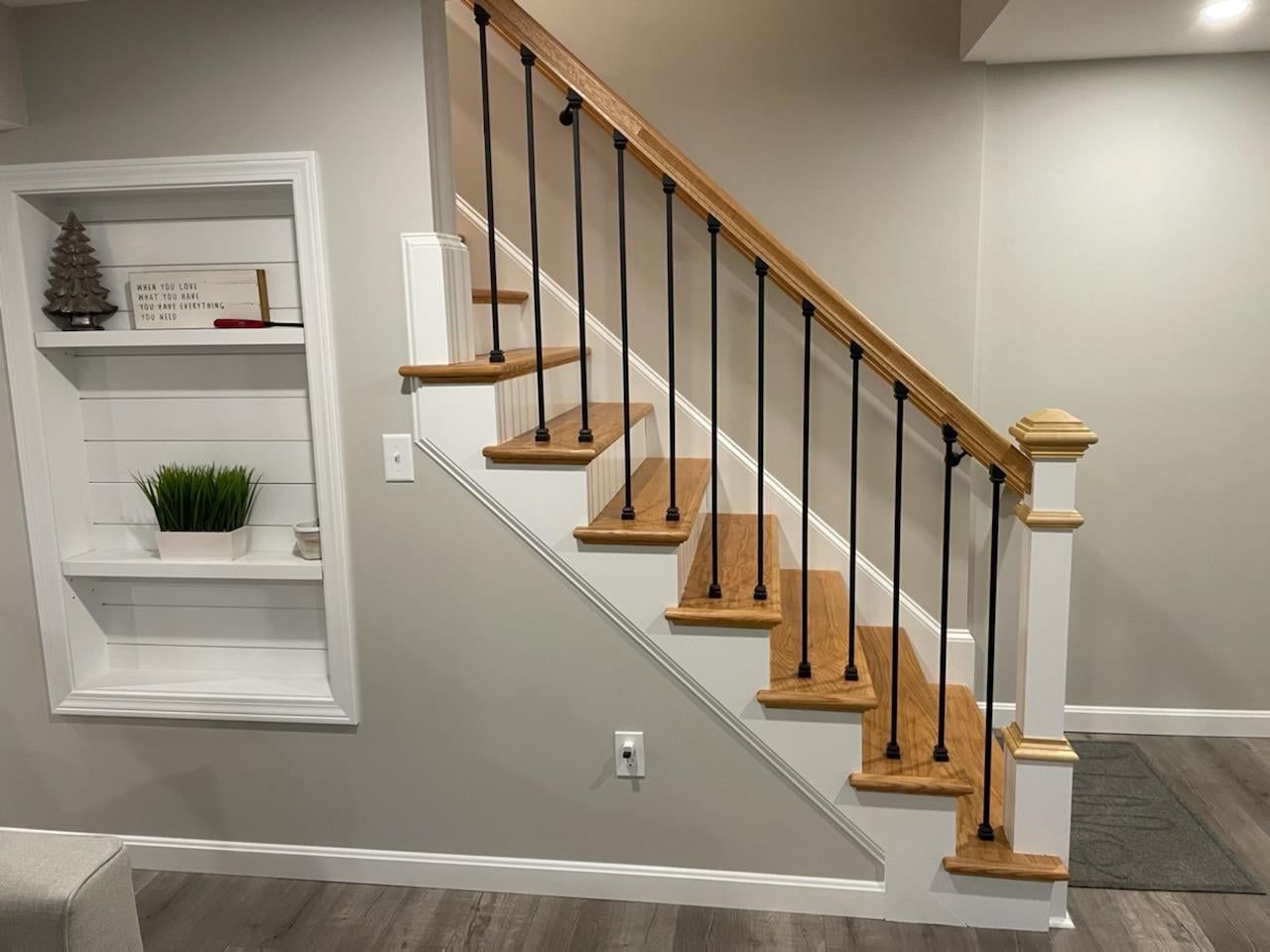 A wooden staircase with a metal railing in a basement.