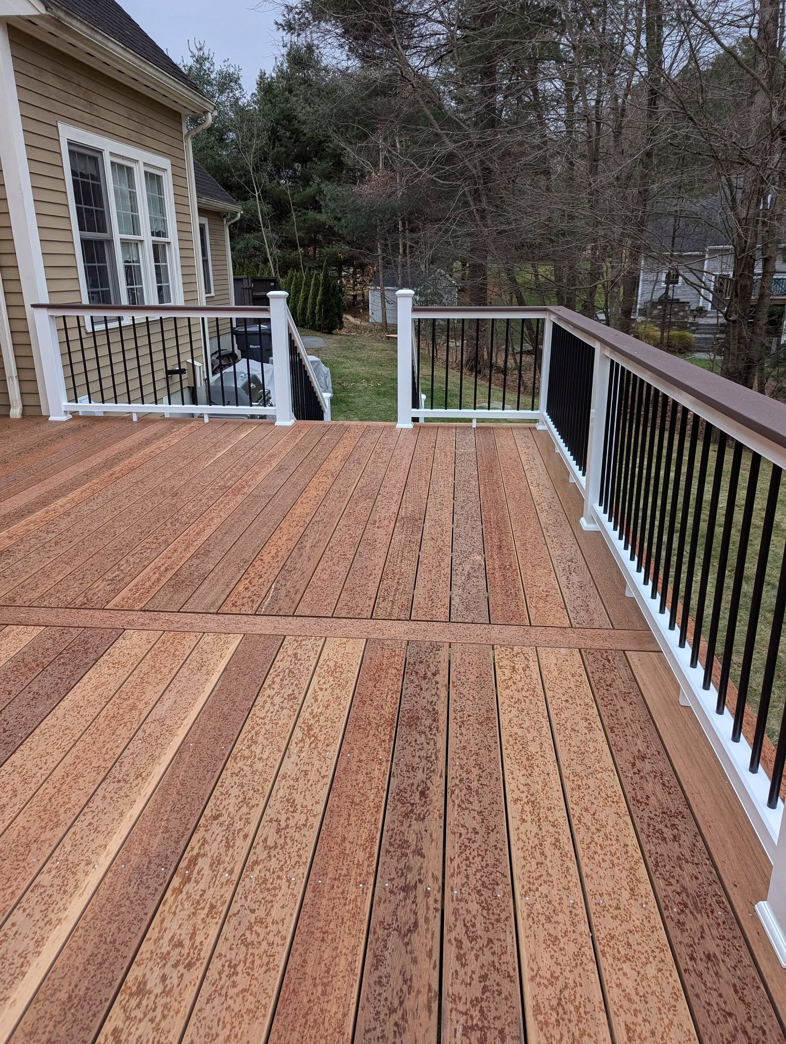 A wooden deck with a white railing and a house in the background.