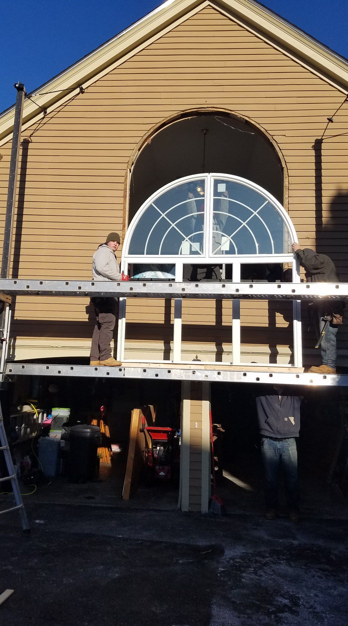 A man is standing on a ladder in front of a building.