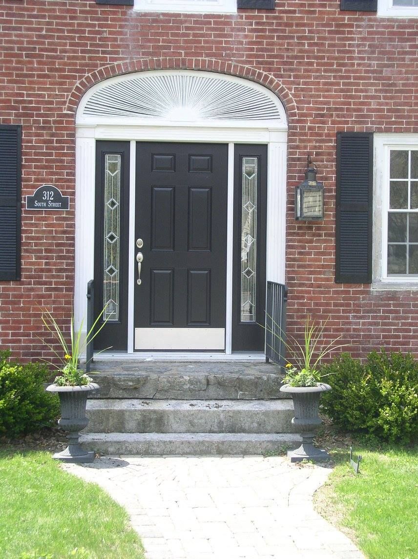 A brick house with black shutters and a black door.