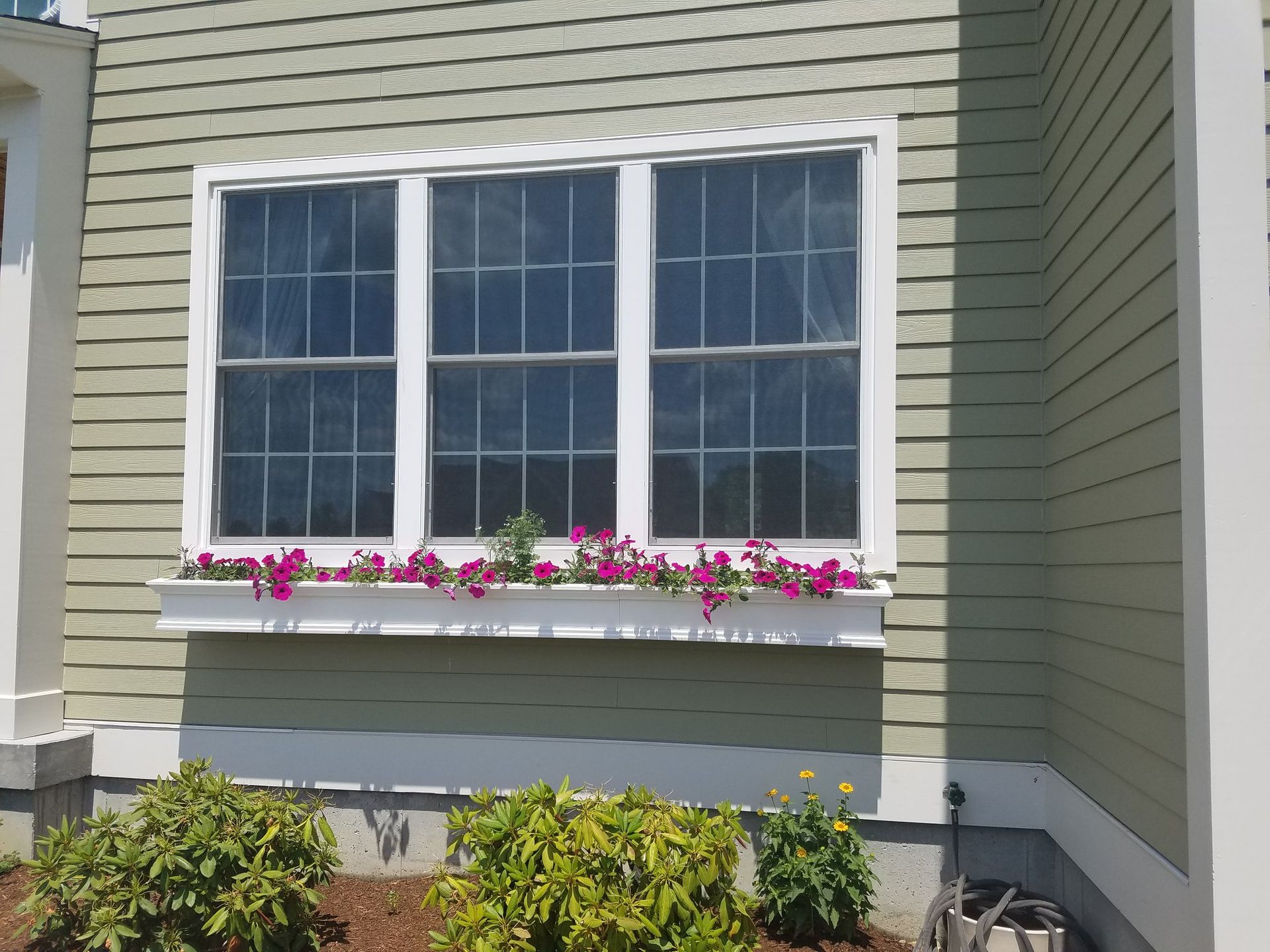 A window with flowers in it on the side of a house.