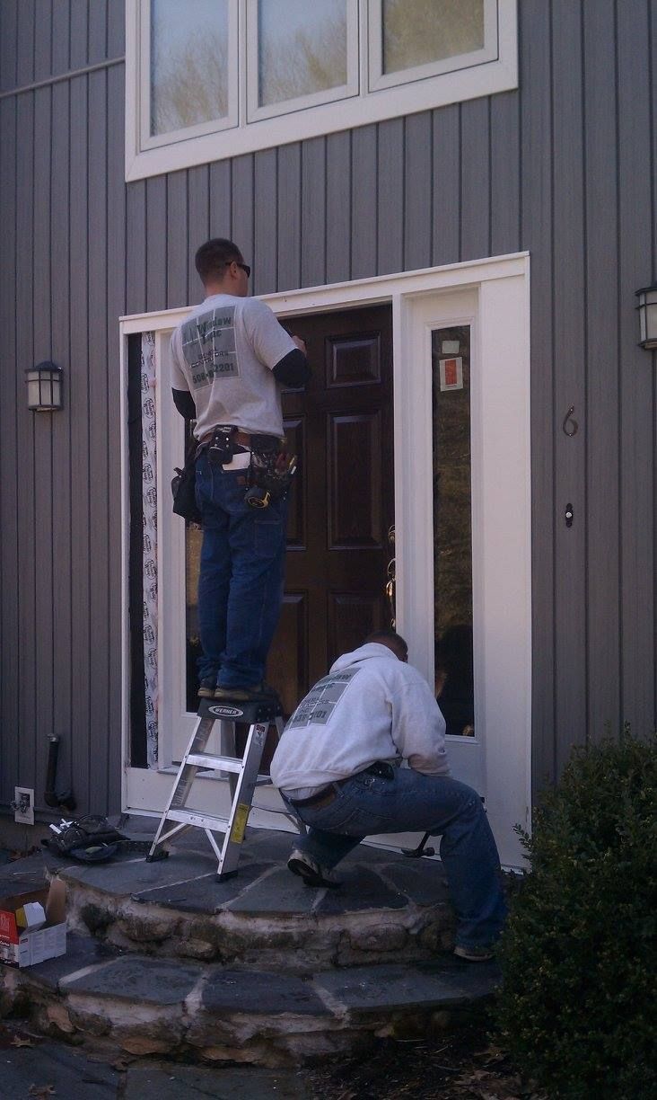 Two men are working on a front door of a house.