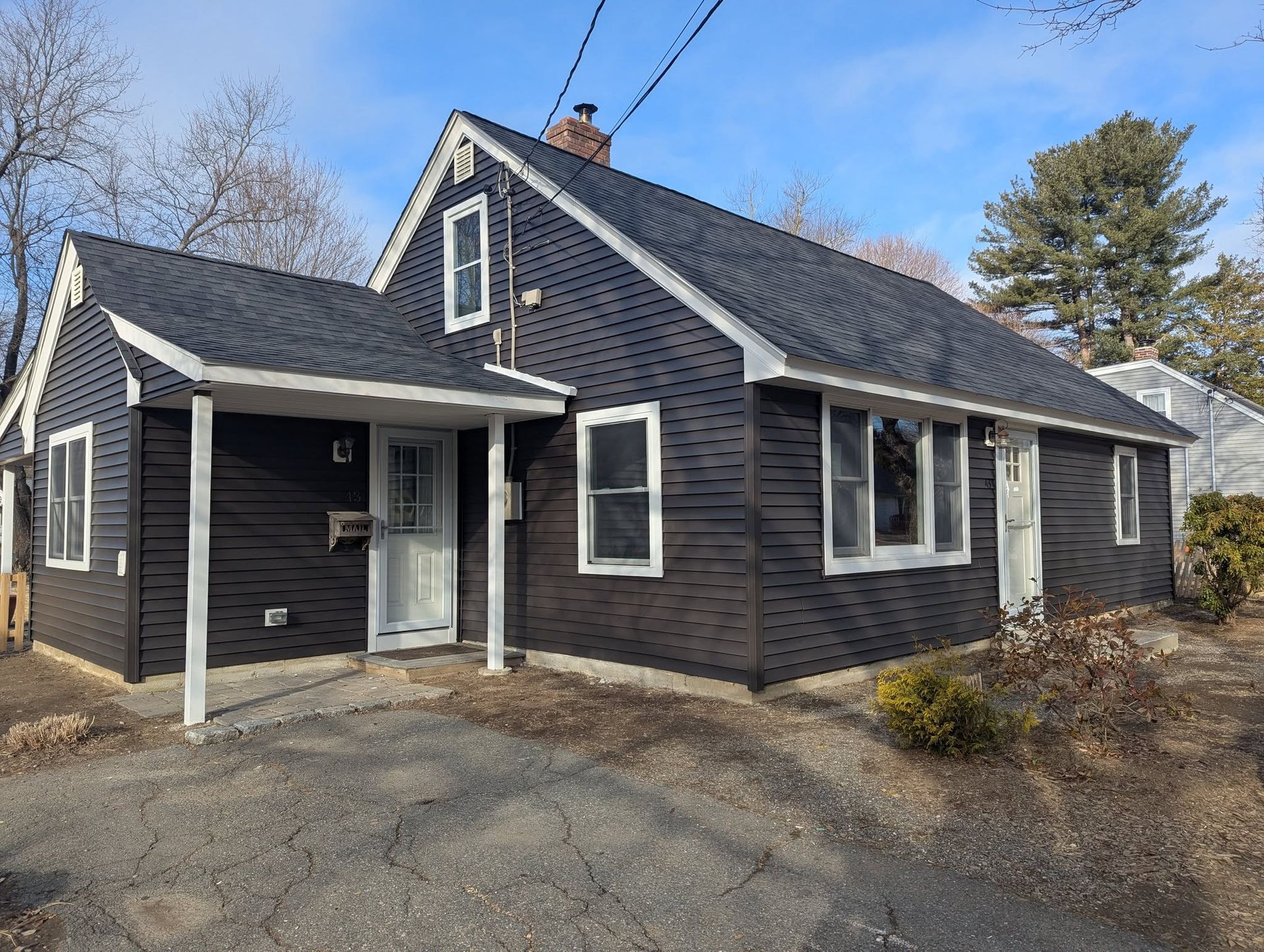 A black house with a white porch and a black roof.