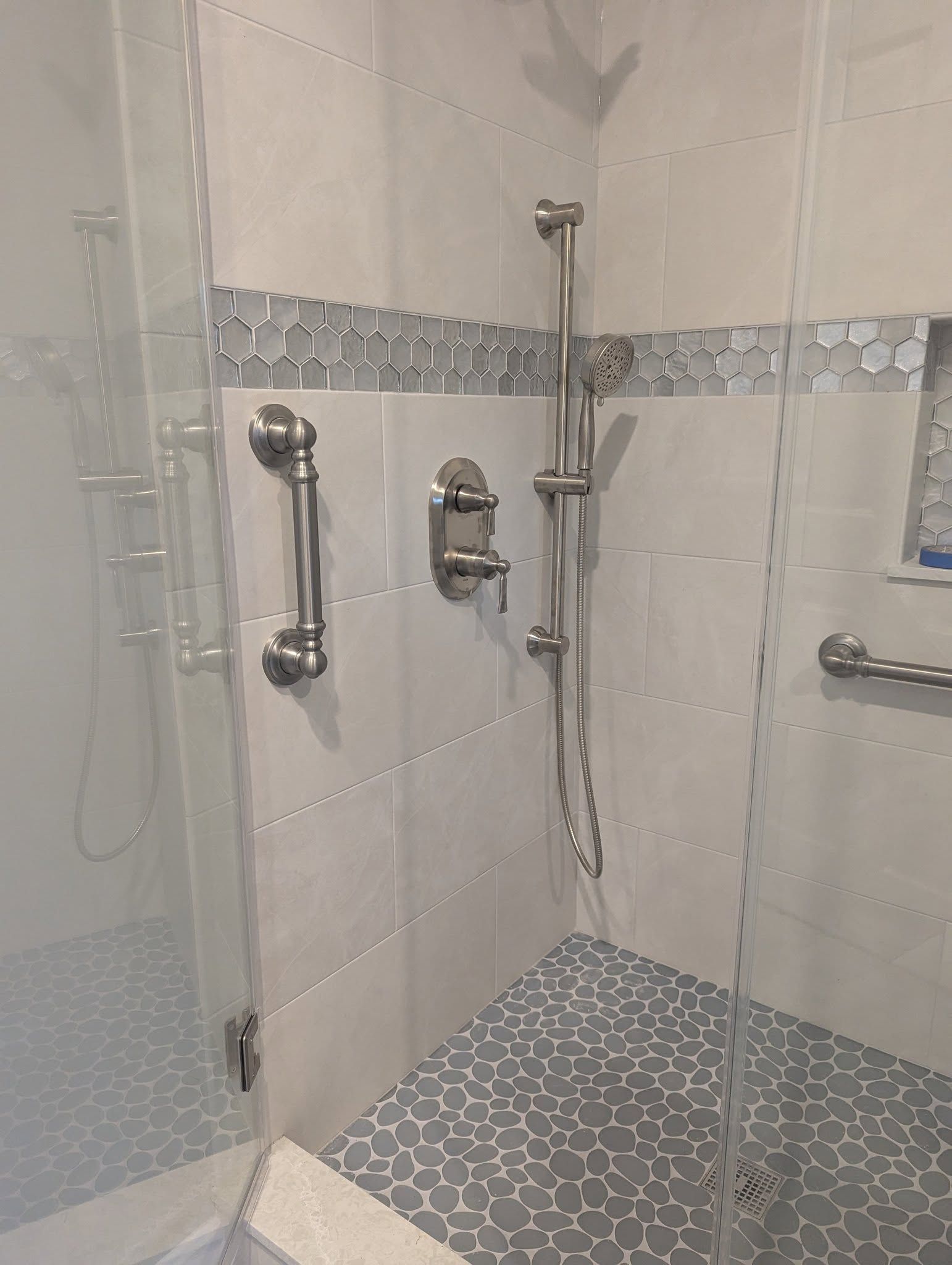 A bathroom with a walk-in shower and a glass door.