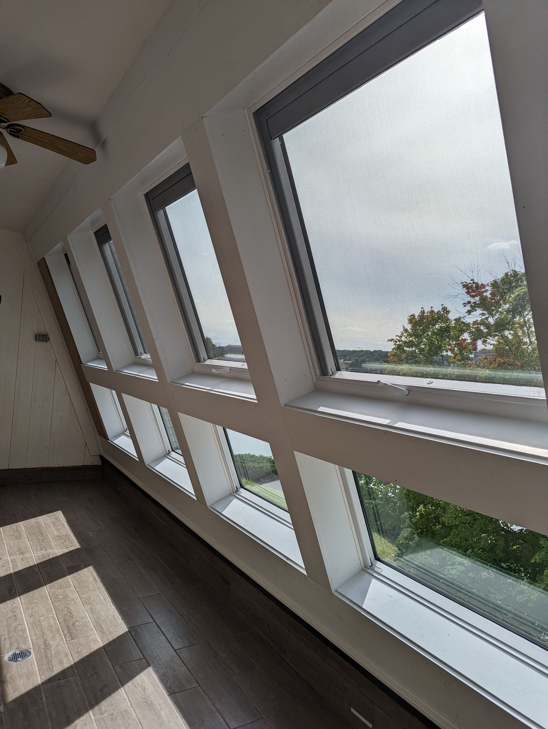 A room with a lot of windows and a ceiling fan