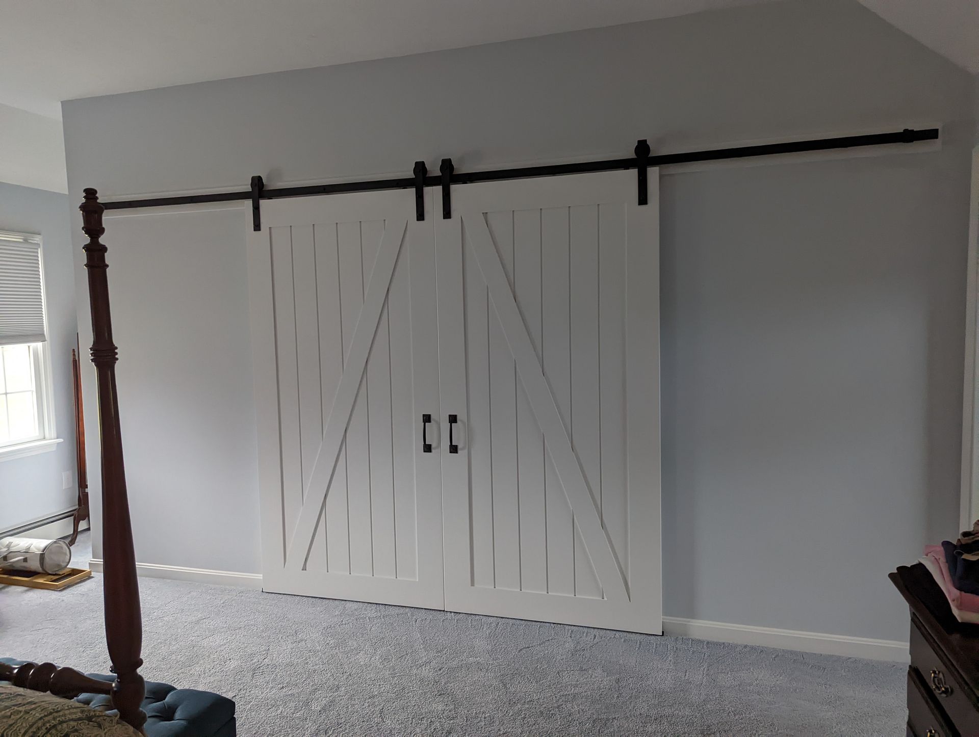 A bedroom with a sliding barn door and a four poster bed.