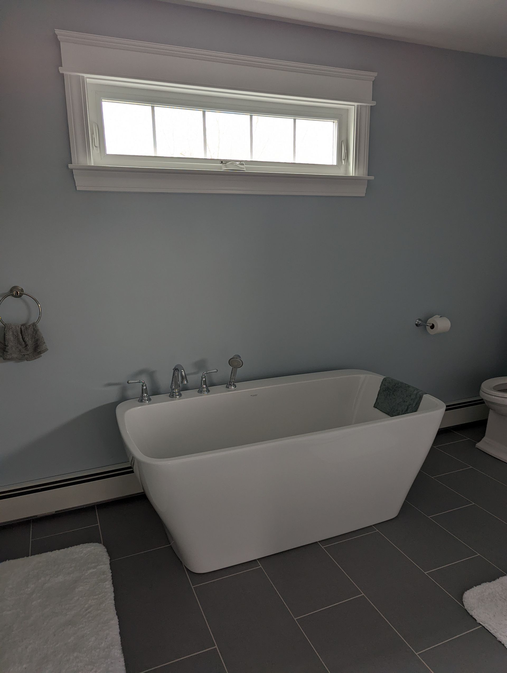 A bathroom with a tub, toilet, and window.