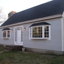 A white house with a black roof and a lot of windows.