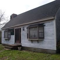 A small white house with a black roof and a lot of windows.