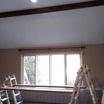 A room with a large window and a ladder in front of it.