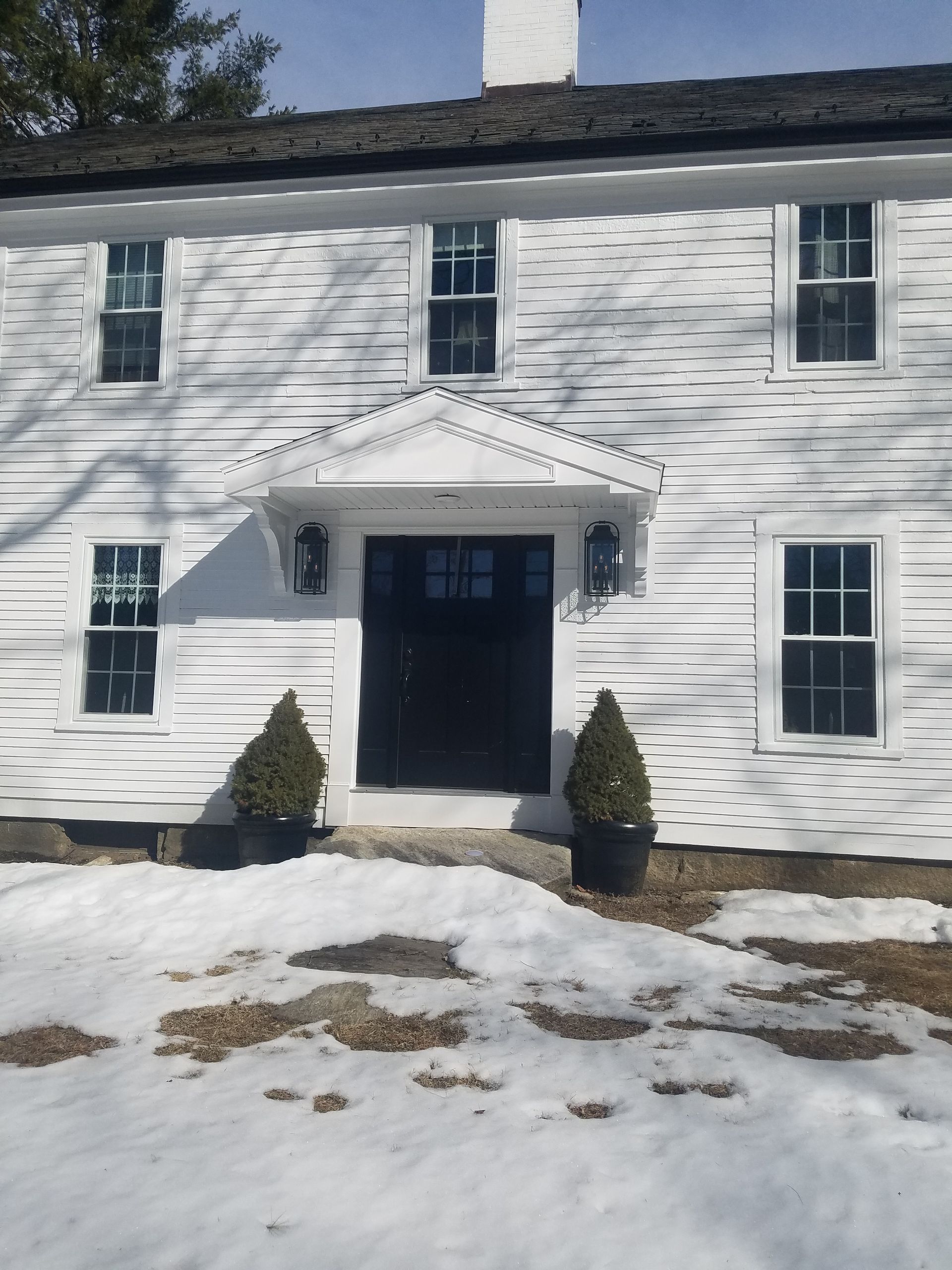 A white house with snow on the ground in front of it