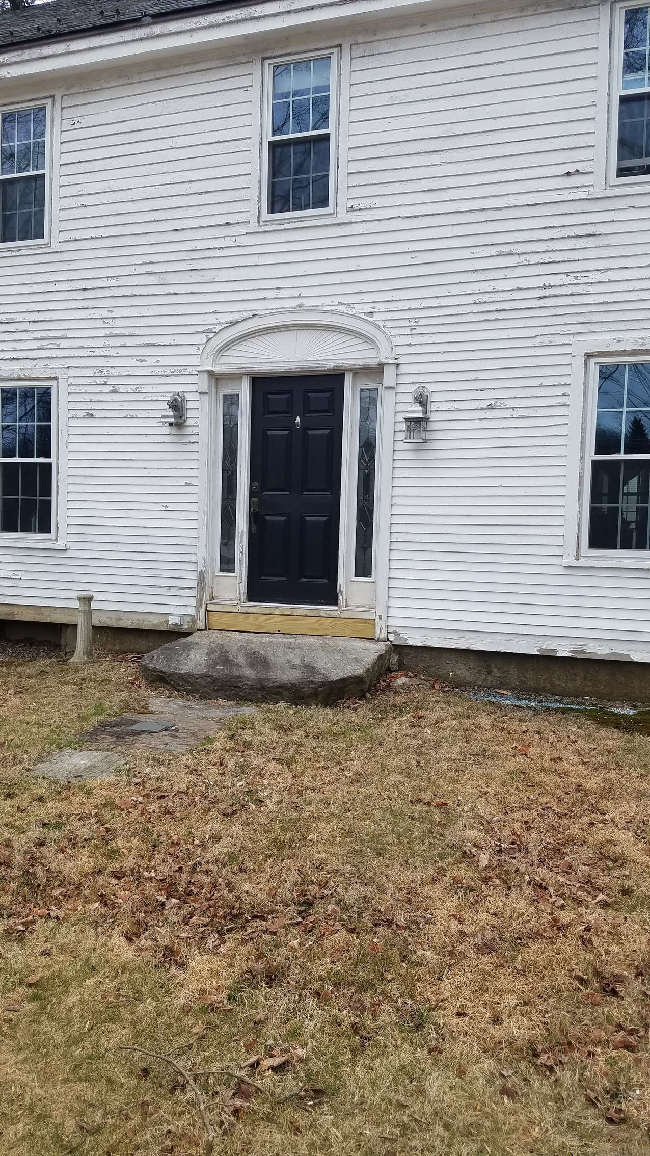 The front of a white house with a black door and windows.