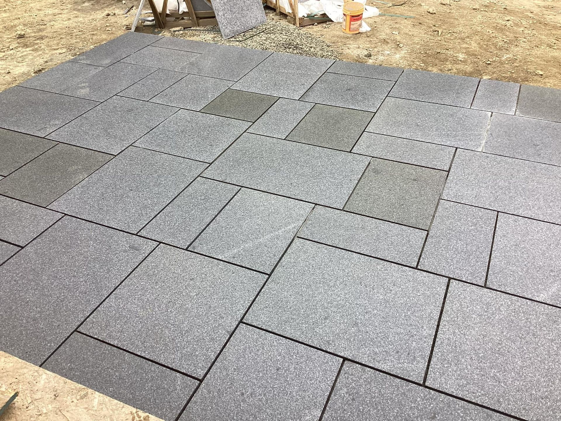 Gray stone pavers arranged in a rectangular pattern on a dirt surface.