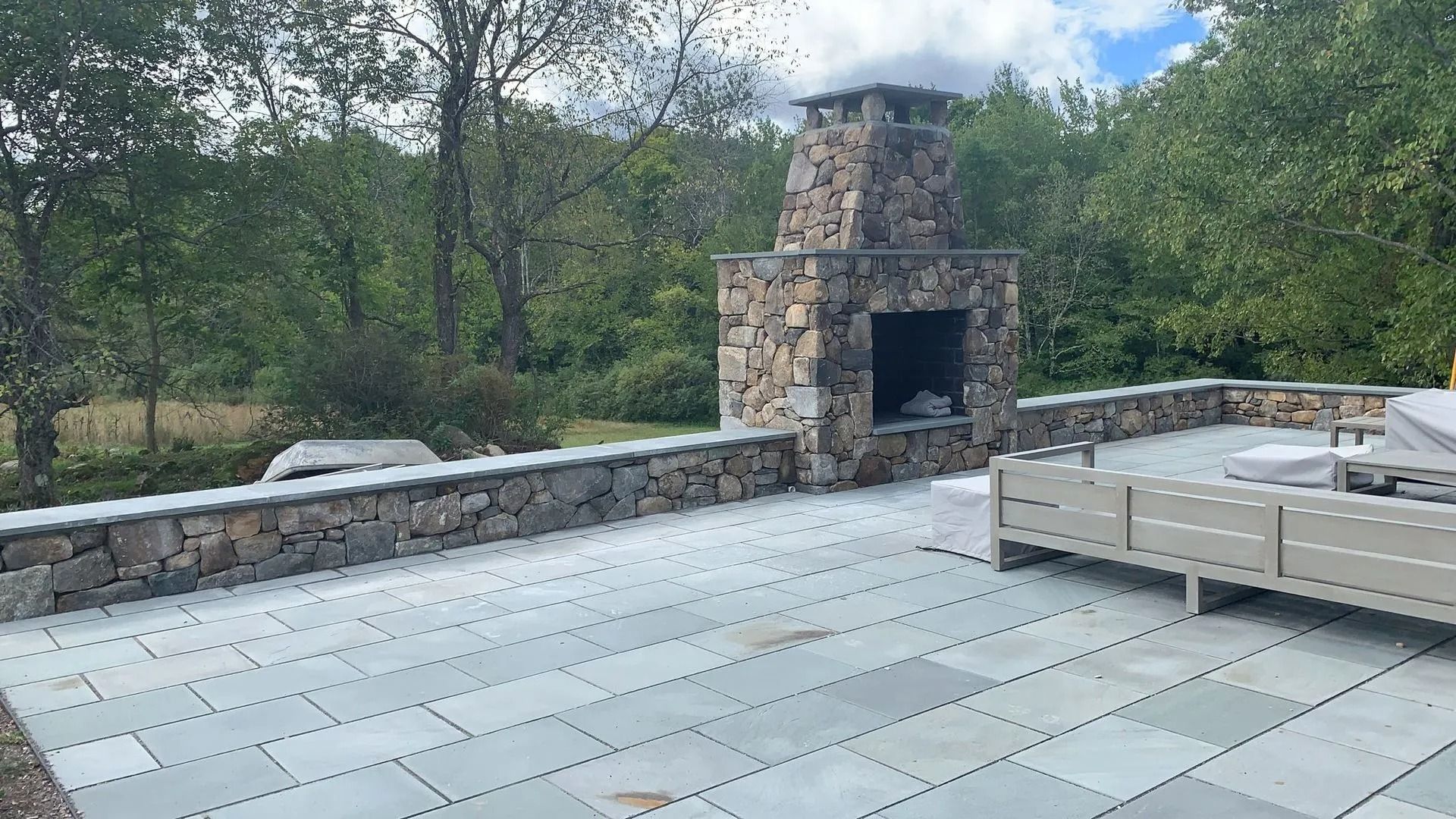 Patio with stone fireplace and walls; blue stone pavers; outdoor seating.