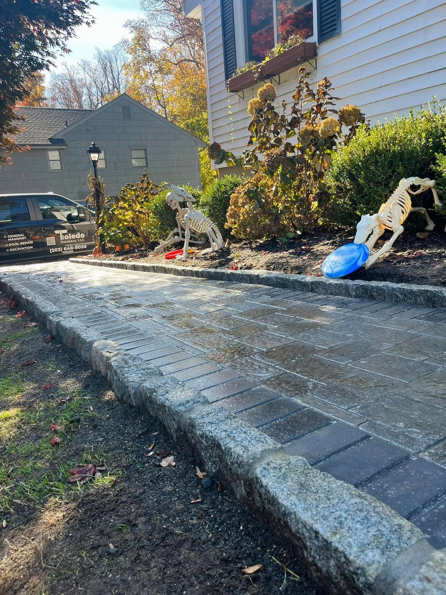 Brick walkway leads to a house with decorations; a Dalmatian and person float, a car parked in the left.