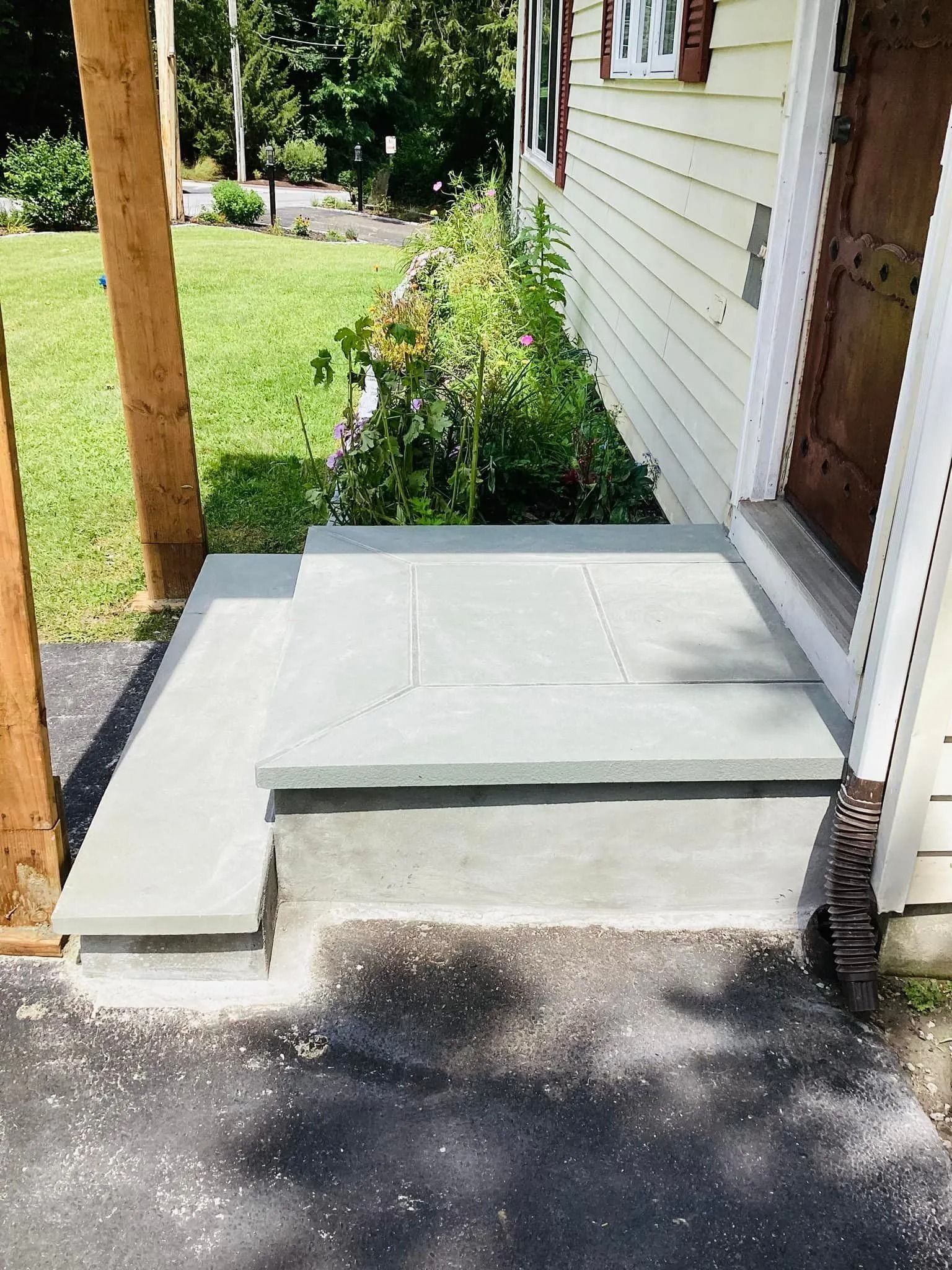 Concrete steps leading to a light yellow house with a brown door.