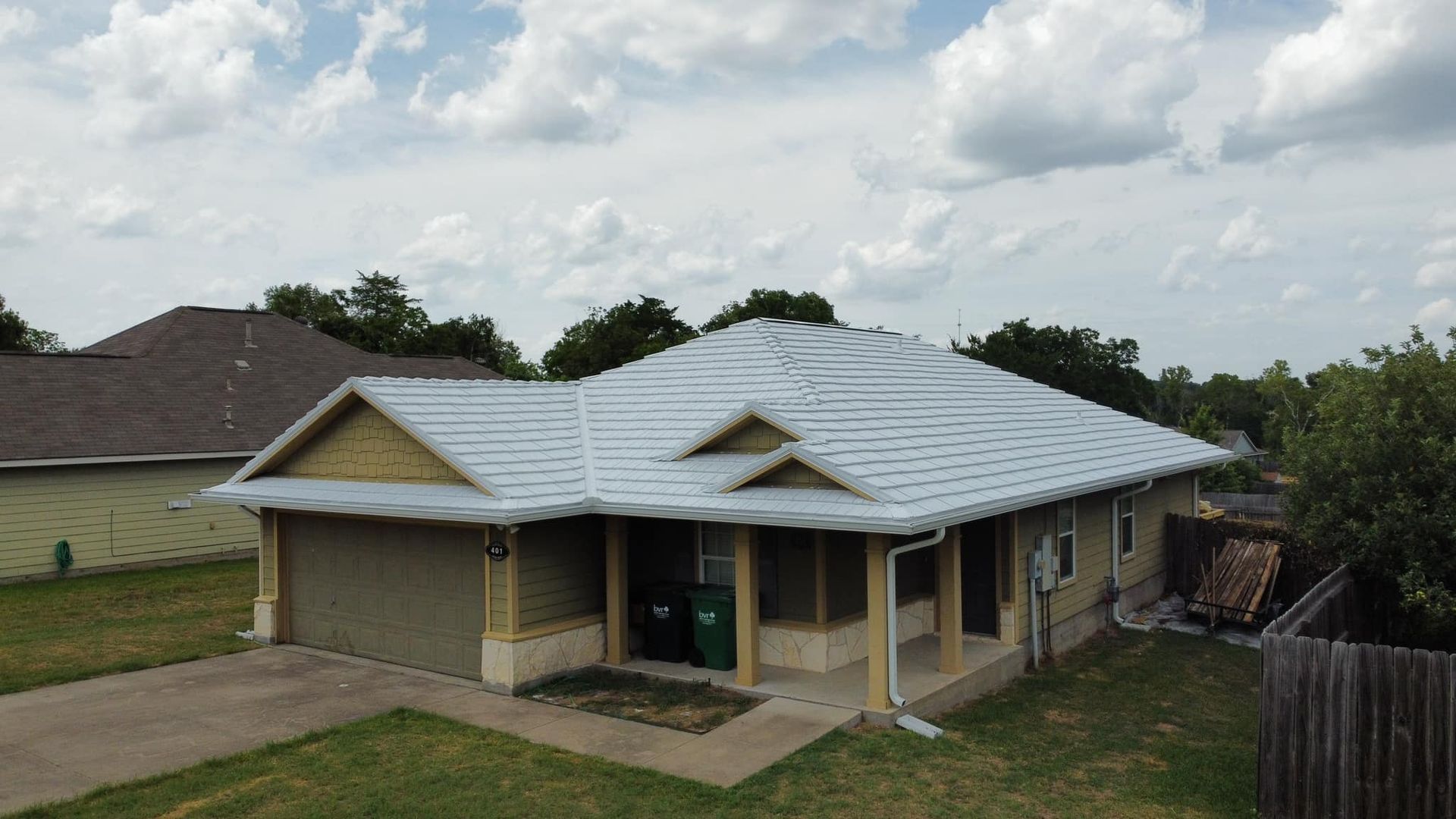 A light-colored house with a light gray roof and green lawn on a cloudy day.