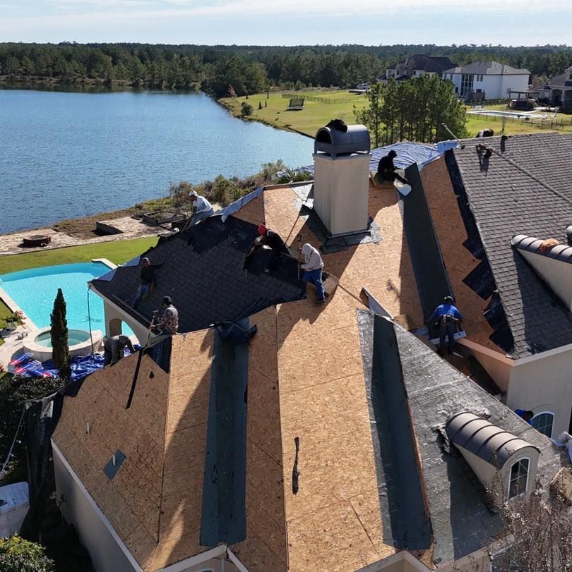 Roofers working on a house with a lake and golf course in the background.