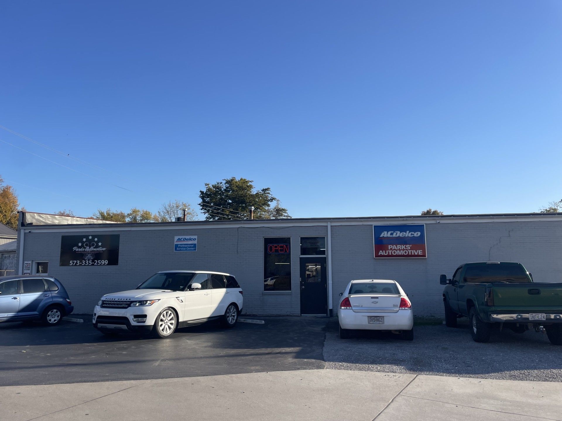 Auto repair shop with parked cars under a blue sky; an Auto Value sign is visible.