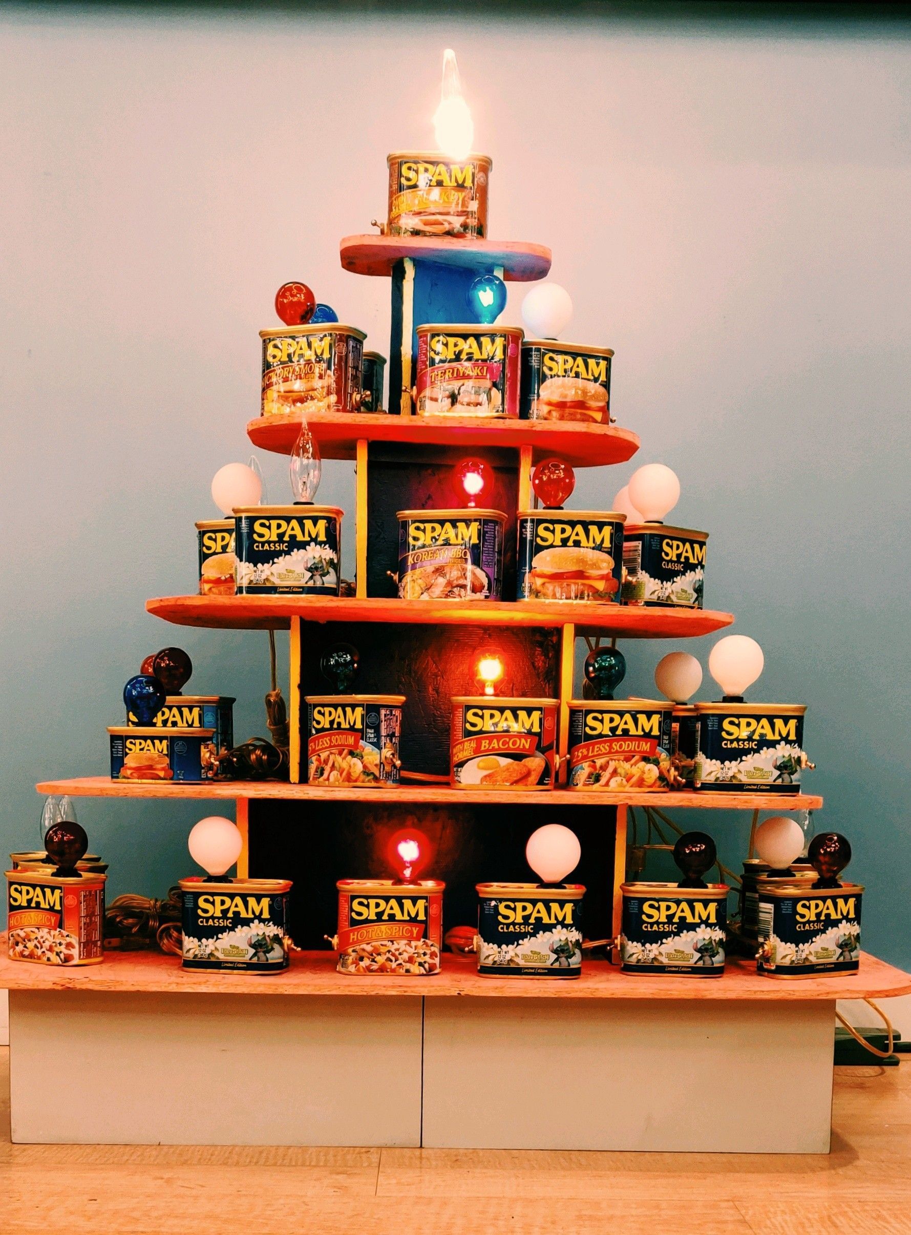 A tiered display shaped like a Christmas tree, made from Spam cans, with lights and decorations.