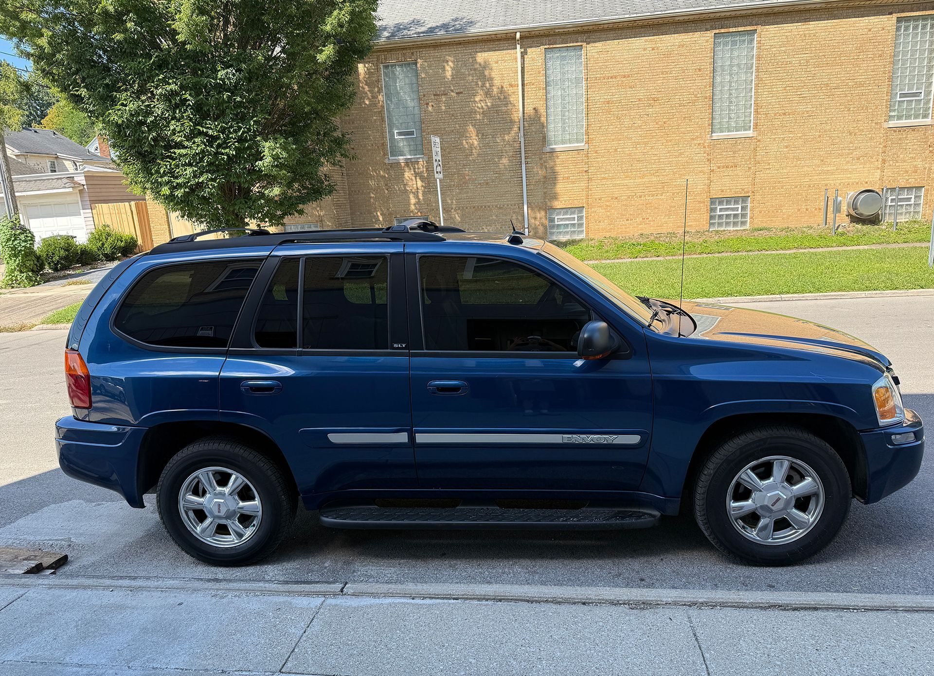 Blue SUV parked on a city street, in front of a brick building.