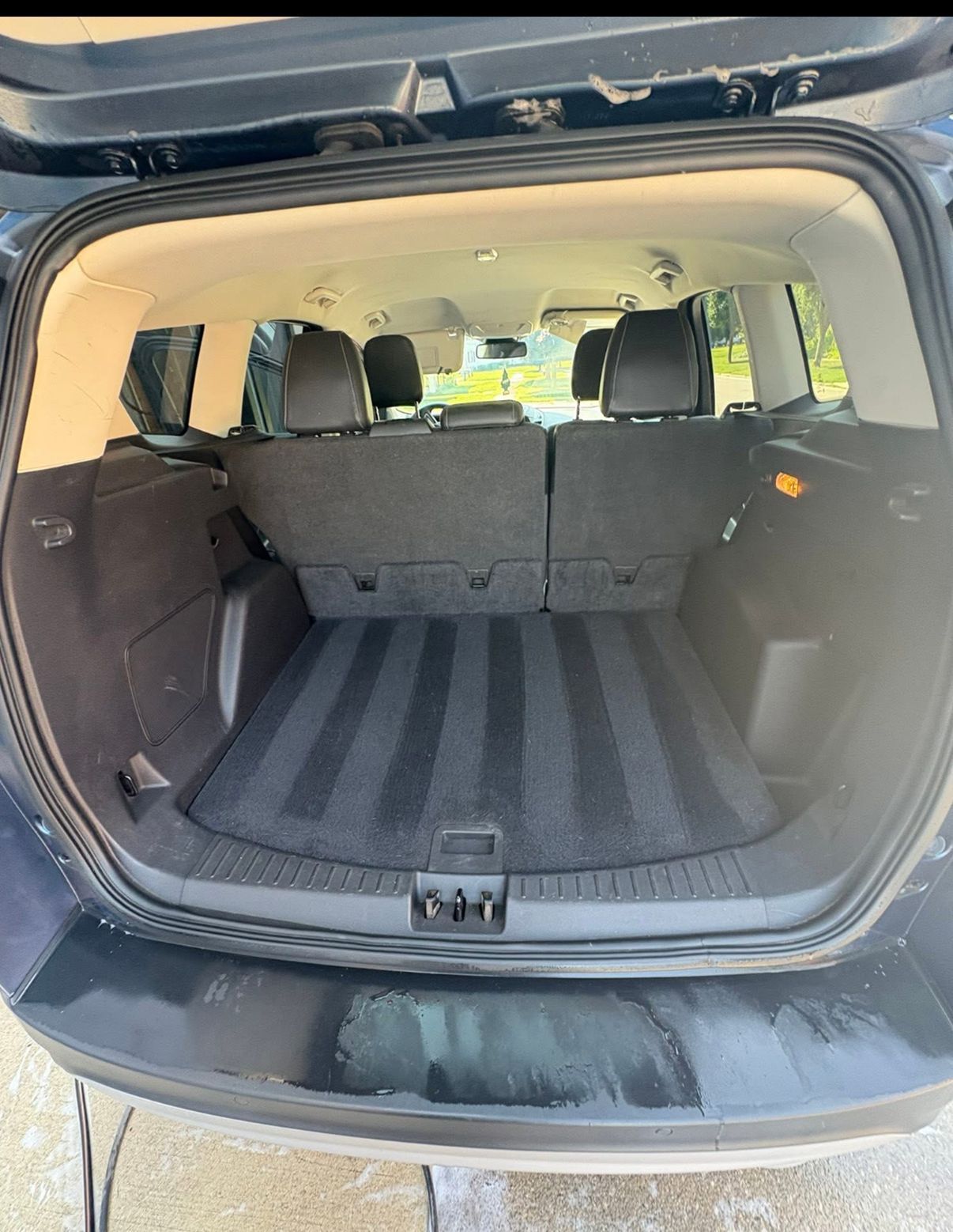 Open trunk of a black SUV with clean, striped carpet. Rear seats are upright.