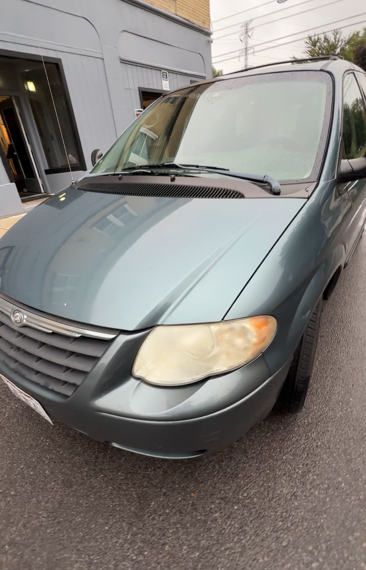 Blue minivan parked in front of a building; daytime.