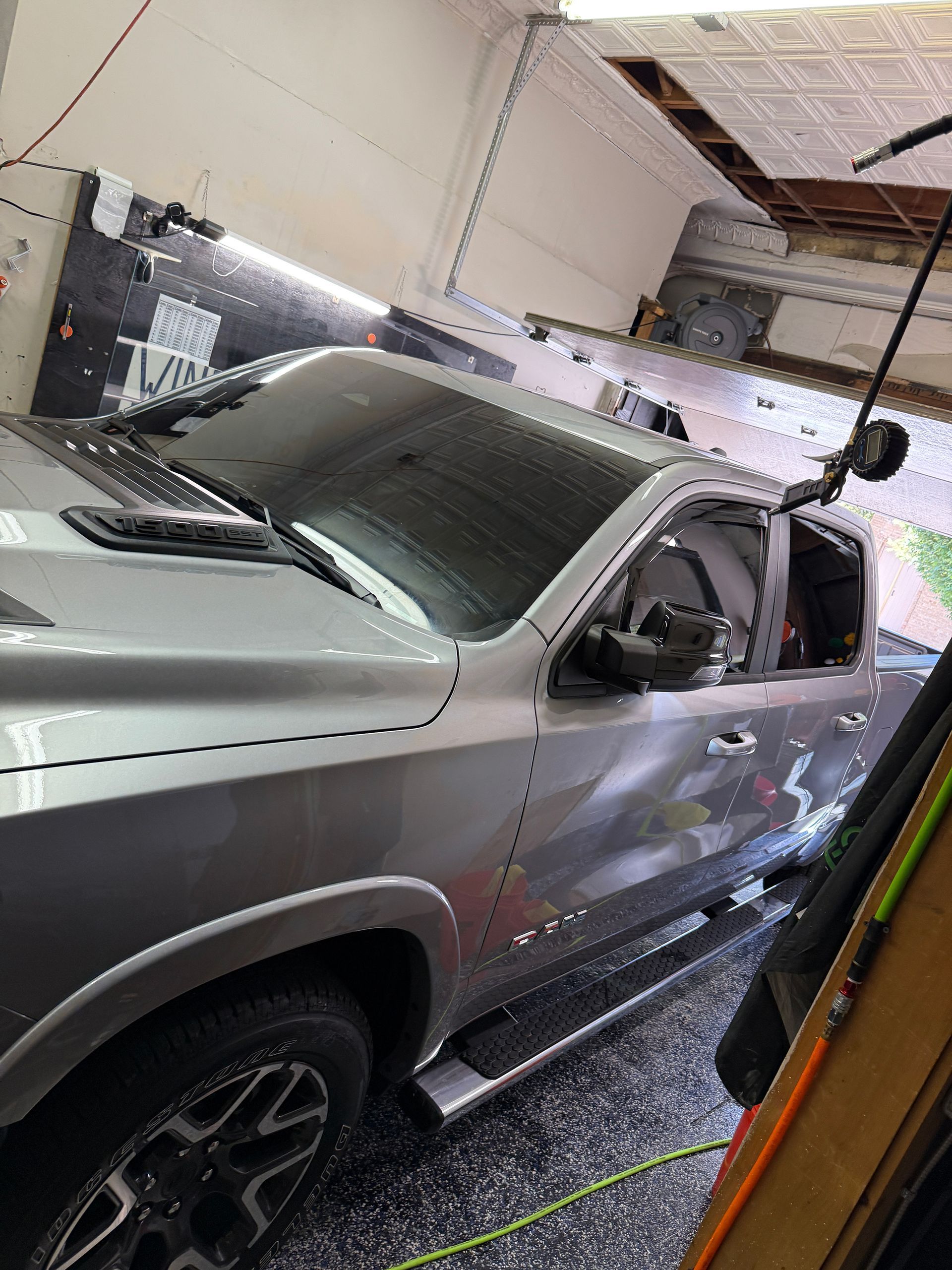 Silver Ram truck in a garage; tinted windows, black wheels, side steps.