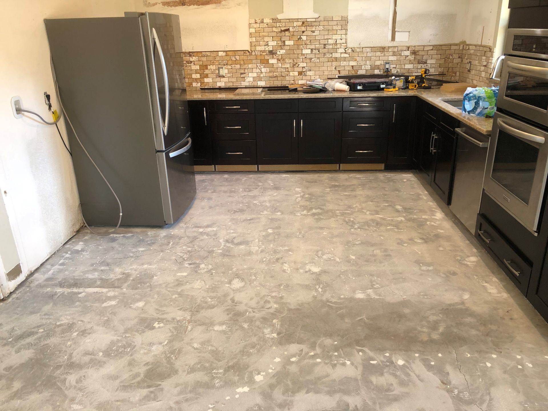 A kitchen with black cabinets and stainless steel appliances is being remodeled.