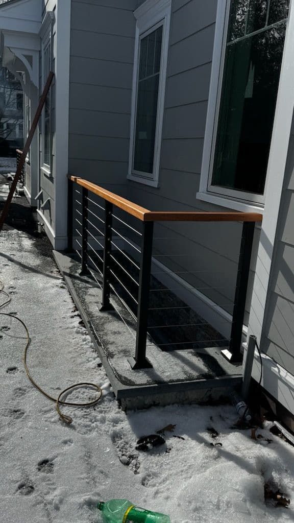 A wooden railing is being installed on the side of a house.