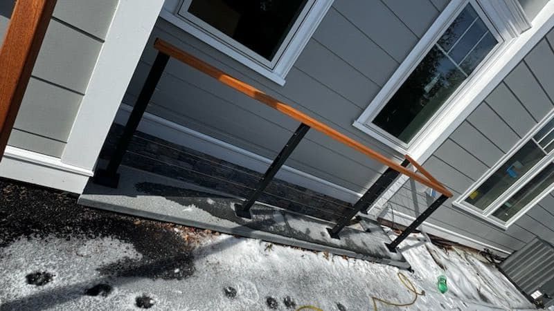 A wooden railing is being installed on the side of a house.