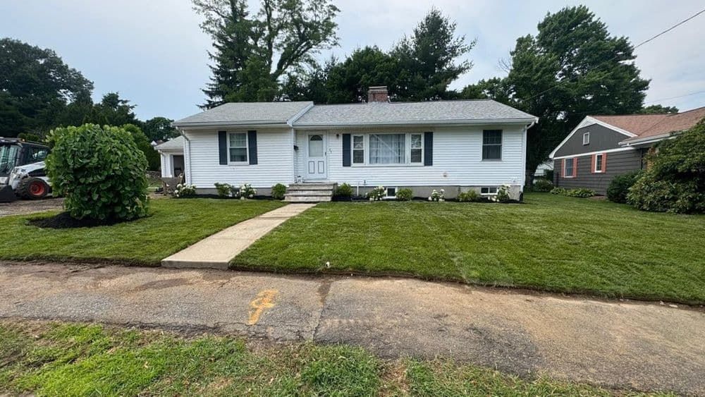 A white house with a tractor parked in front of it.