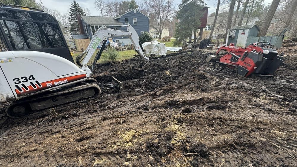 A bulldozer and a stump grinder are sitting in a muddy field.