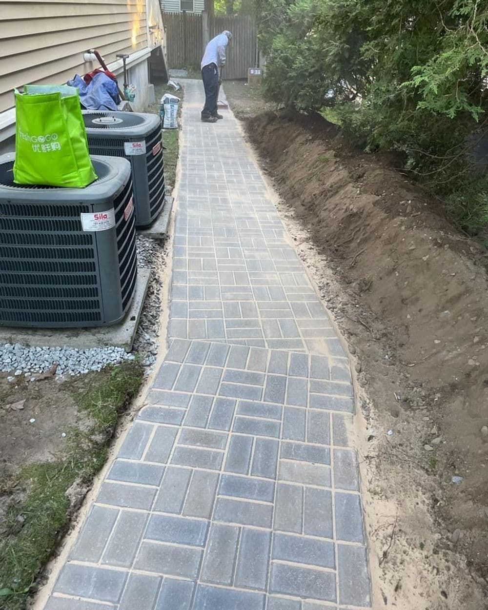 A man is standing on a sidewalk next to a staircase.