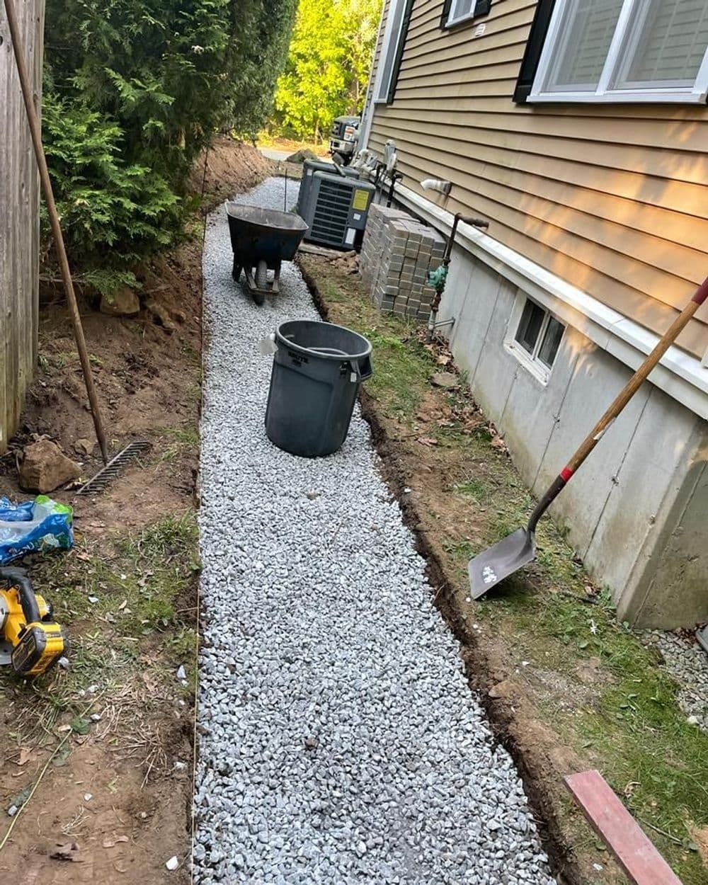 A gravel walkway is being built in front of a house.