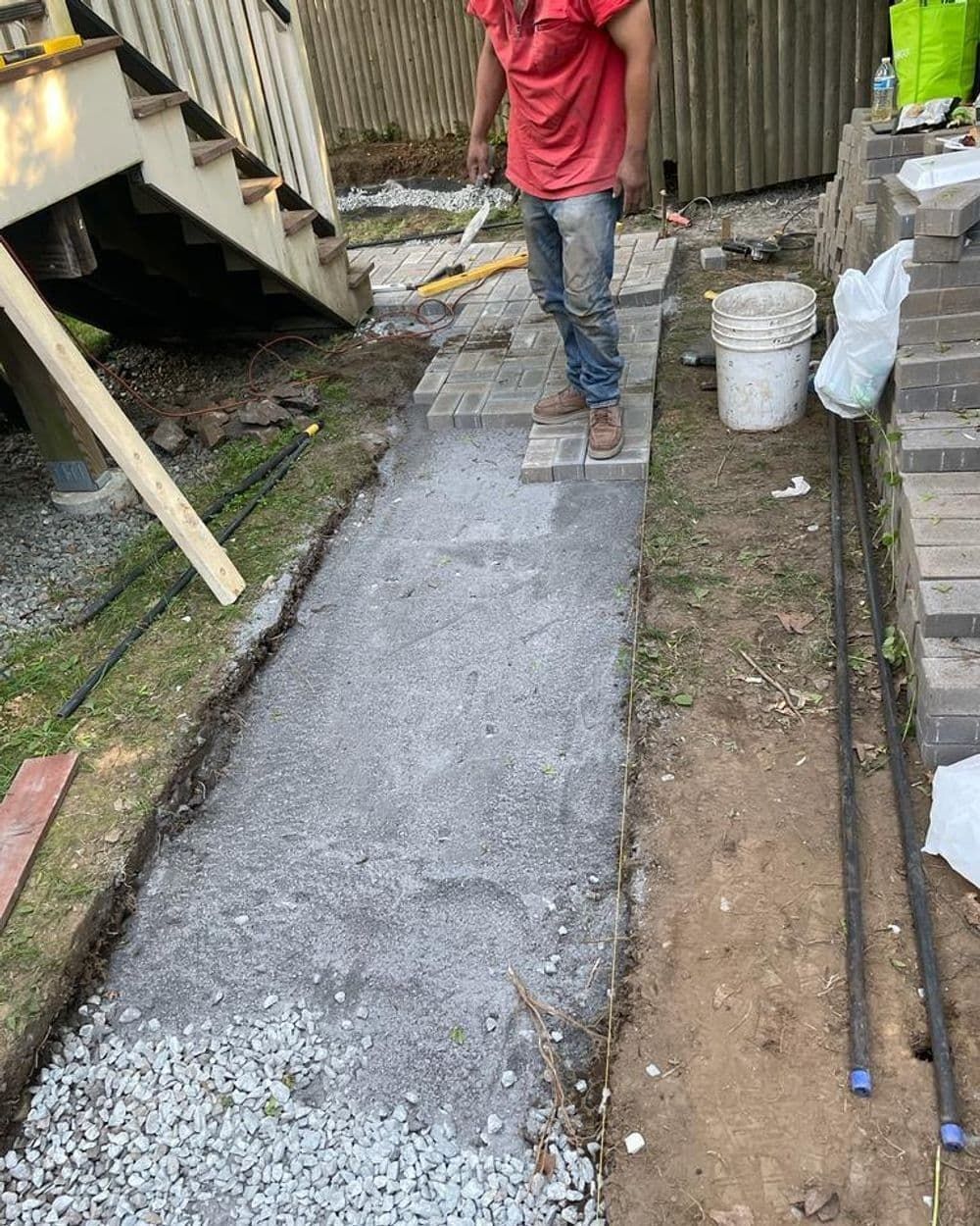A man is standing on a sidewalk holding a shovel.