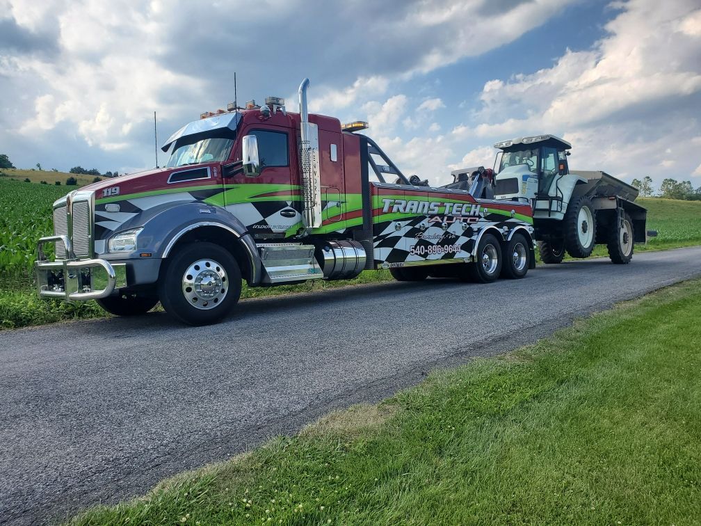 Custom red-and-green semi truck hauling a trailer on a rural road under cloudy skies