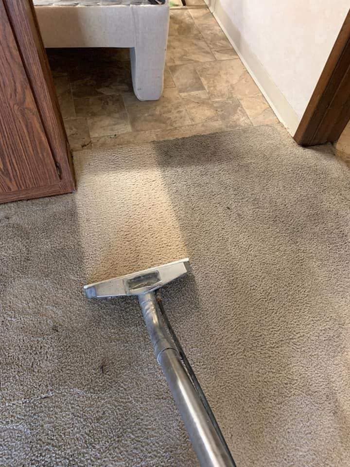 A vacuum cleaner is cleaning a carpet in a room.