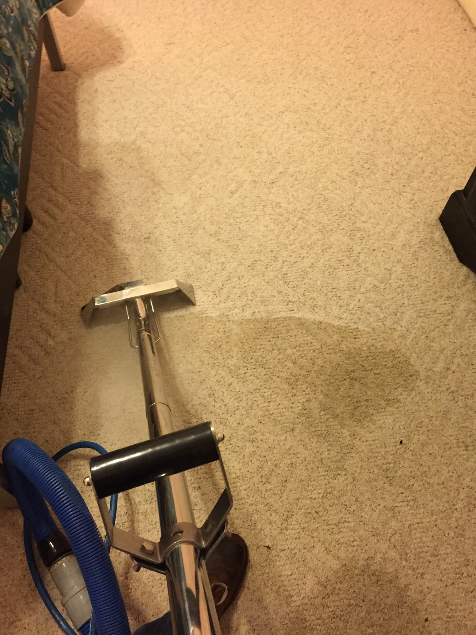 A vacuum cleaner is cleaning a carpet in a living room.