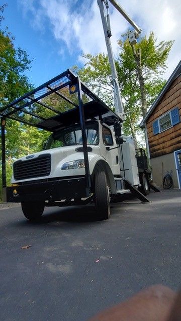 A white truck with a crane on top of it is parked in front of a house