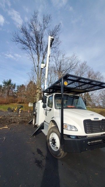 A white truck with a crane on top of it is parked in a parking lot