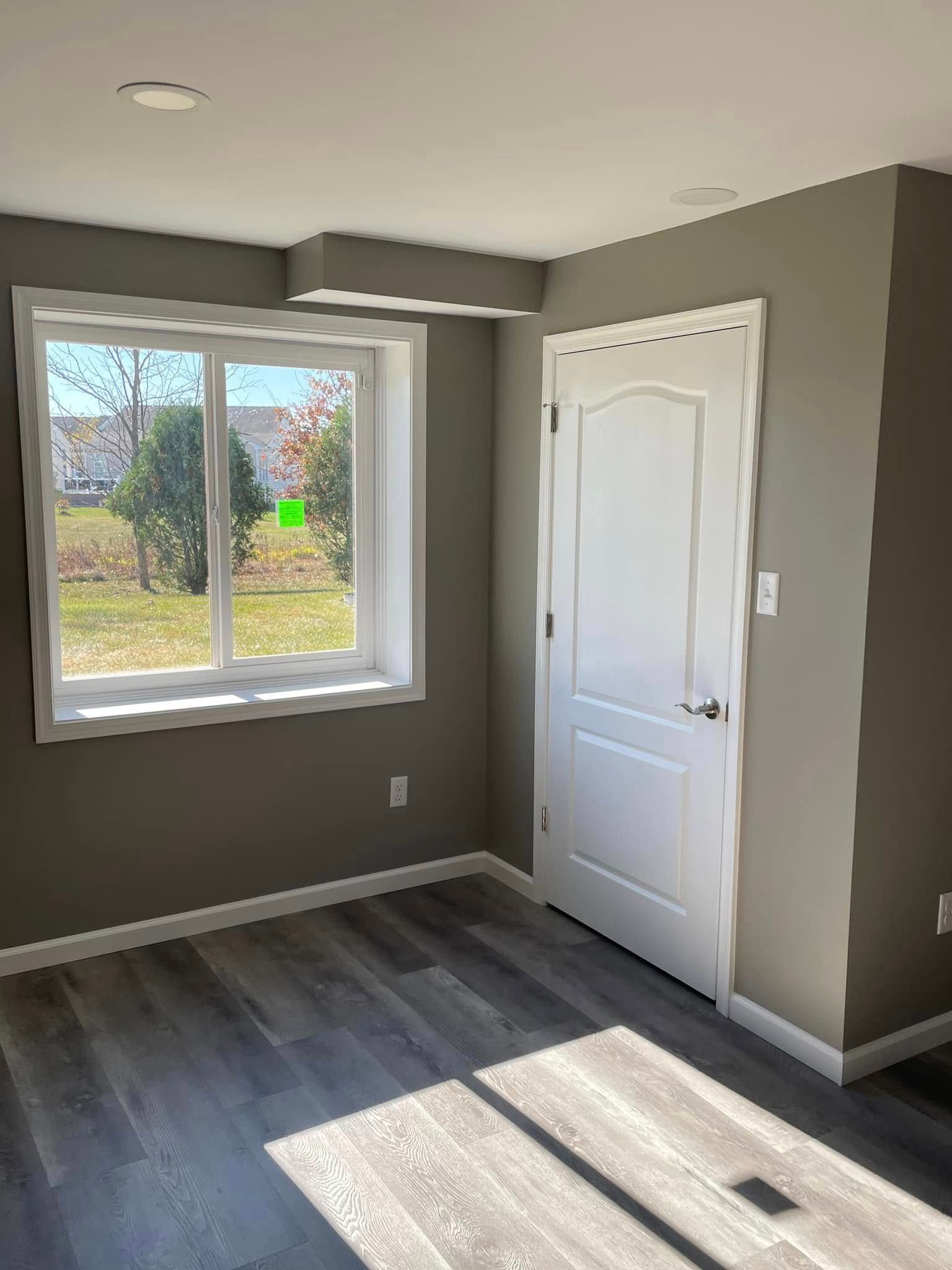 A room with a large window and a white door.